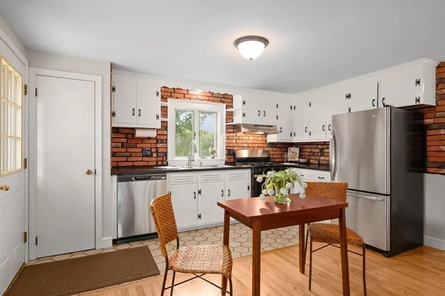 a kitchen with stainless steel appliances a refrigerator a stove a dining table and chairs with wooden floor