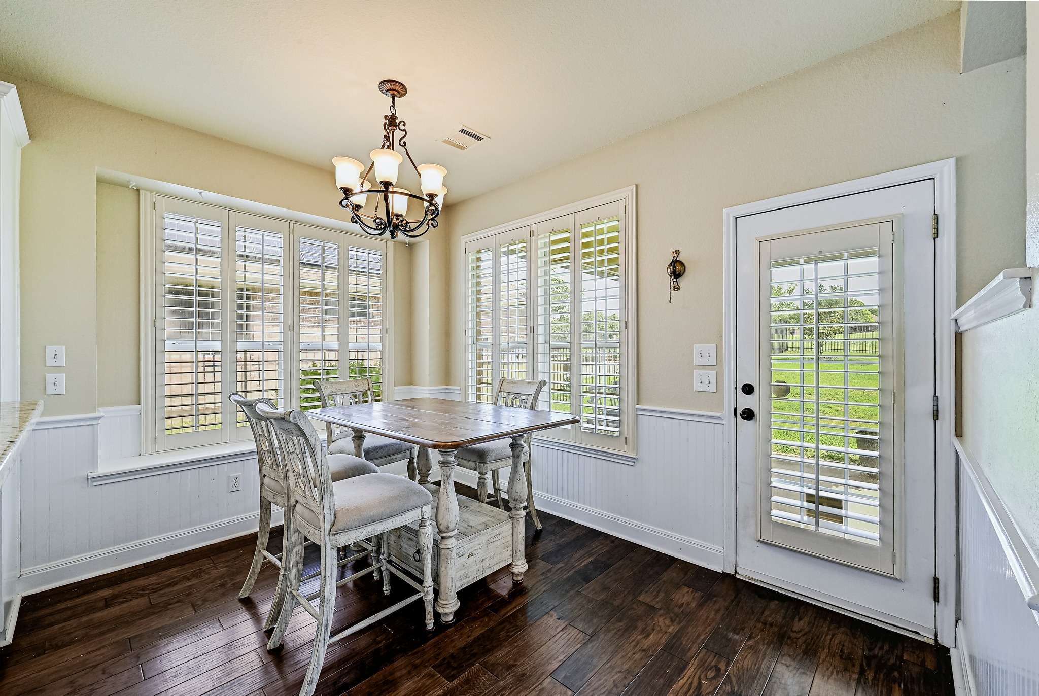 2408 Amen Corner Road Pflugerville, TX 78660 - Photo 17 of 40 Bright dining area featuring dark wood-finish flooring, white beadboard wainscoting, and a full-light door