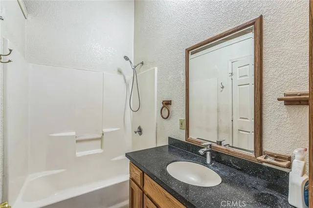 a bathroom with a granite countertop sink a mirror and a shower