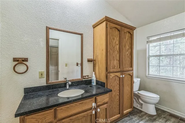 a bathroom with a granite countertop sink toilet a mirror and shower