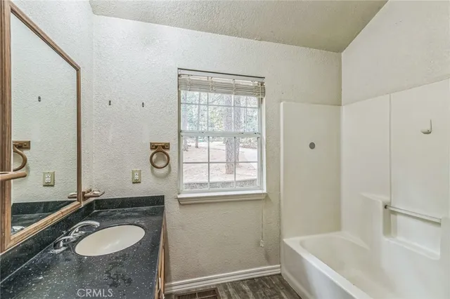 a bathroom with a granite countertop sink and mirror with bathtub