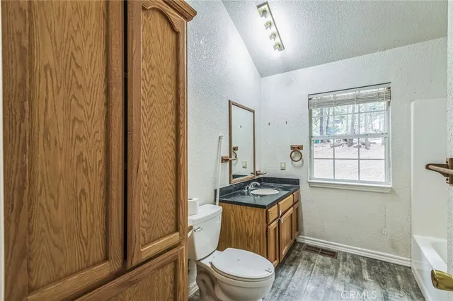 a bathroom with a granite countertop toilet sink and mirror