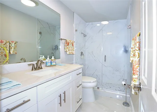 a bathroom with a granite countertop sink toilet and shower