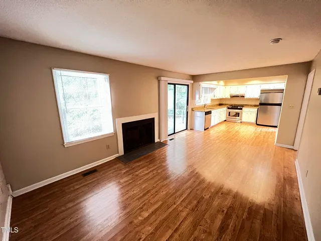 a view of a living room a dining room with wooden floor and a fireplace