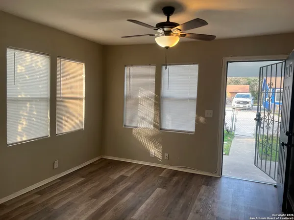 a view of an empty room with wooden floor and a window