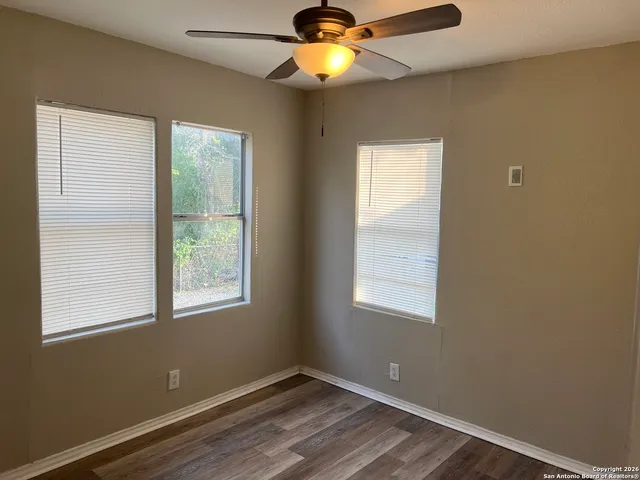 a view of an empty room with window and wooden floor
