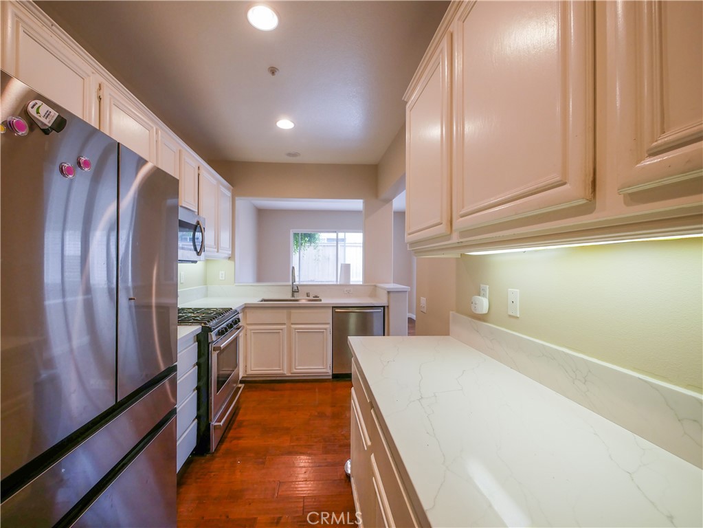 67 Ardmore Irvine, CA 92602 - Photo 11 of 16 a large kitchen with stainless steel appliances granite countertop a refrigerator a sink dishwasher and wooden cabinets with wooden floor