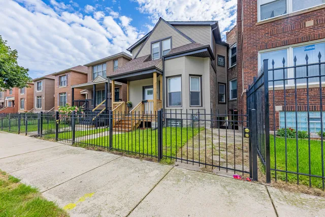 a view of a brick house in front of a yard with plants and brick wall