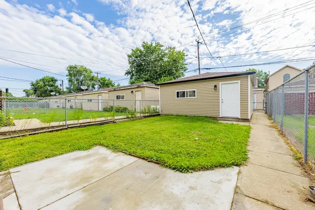 a view of backyard of house with outdoor seating and green bushes