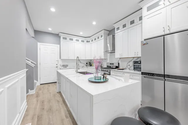 a kitchen with sink a refrigerator and white cabinets
