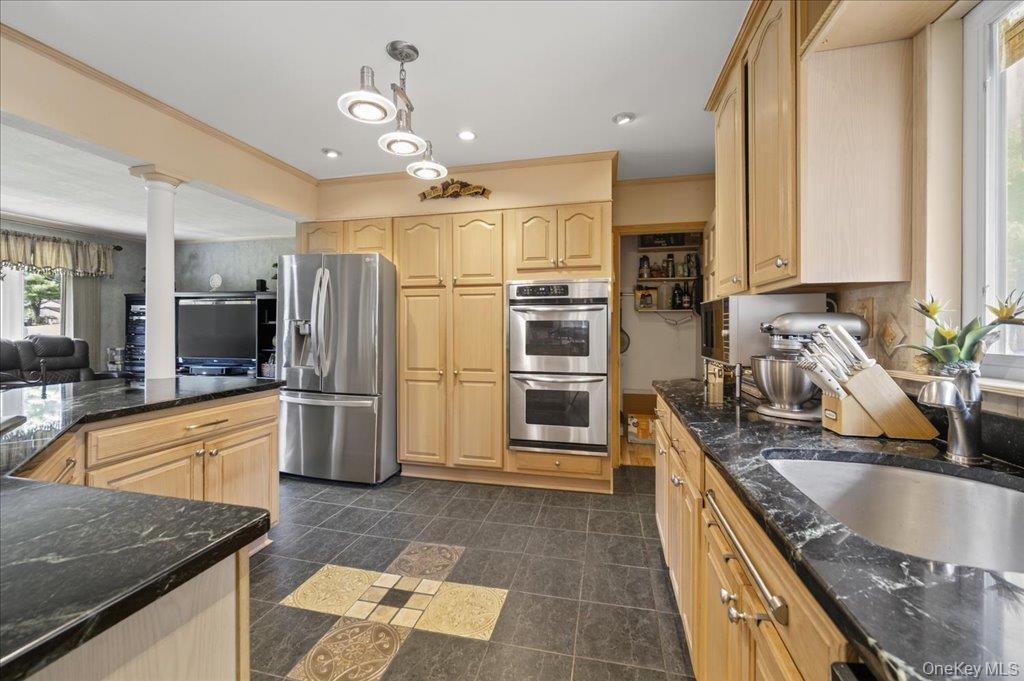 11 Merriewold Lane North Monroe, NY 10950 - Photo 45 of 48 Kitchen featuring appliances with stainless steel finishes, dark stone counters, light brown cabinetry, open floor plan, and hanging light fixtures