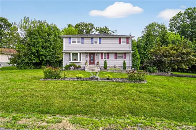 a view of a house with a big yard and large trees