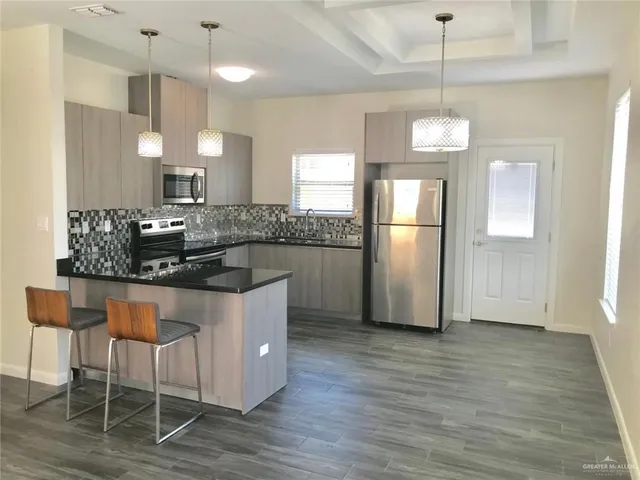 a kitchen with stainless steel appliances kitchen island granite countertop a table chairs and a refrigerator