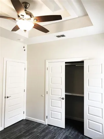 an empty room with wooden floor closet and windows