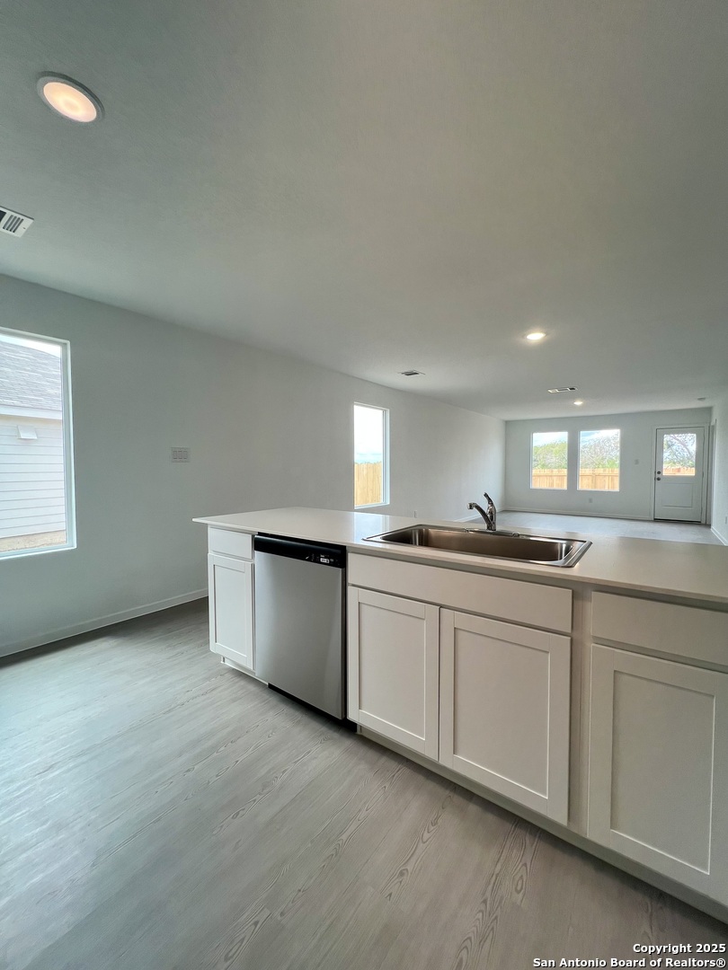 9178 Colonel Trail Seguin, TX 78155 - Photo 13 of 59 a large white kitchen with granite countertop a sink and dishwasher a stove with wooden floors