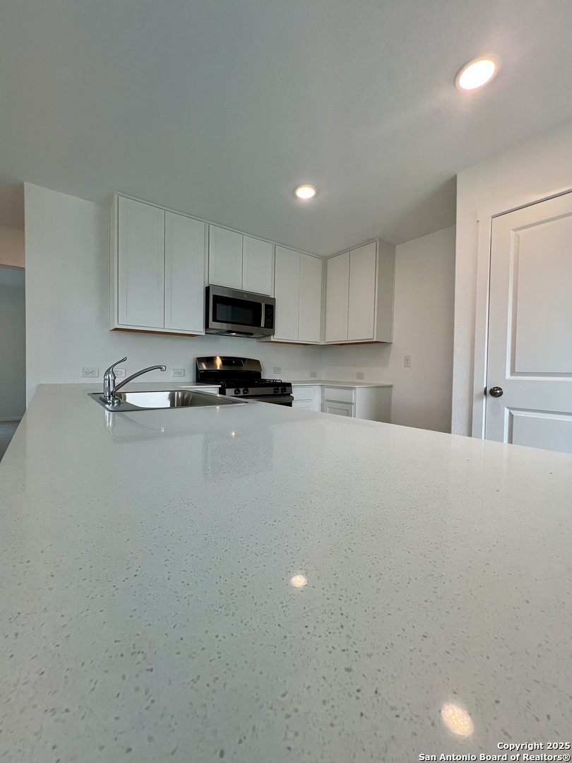 9178 Colonel Trail Seguin, TX 78155 - Photo 15 of 59 a kitchen with kitchen island a stove a sink and a refrigerator