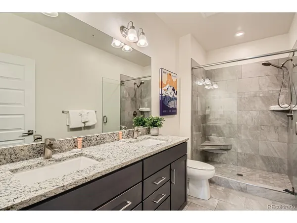 a en suite bathroom with a granite countertop double vanity sink a mirror and a bathtub