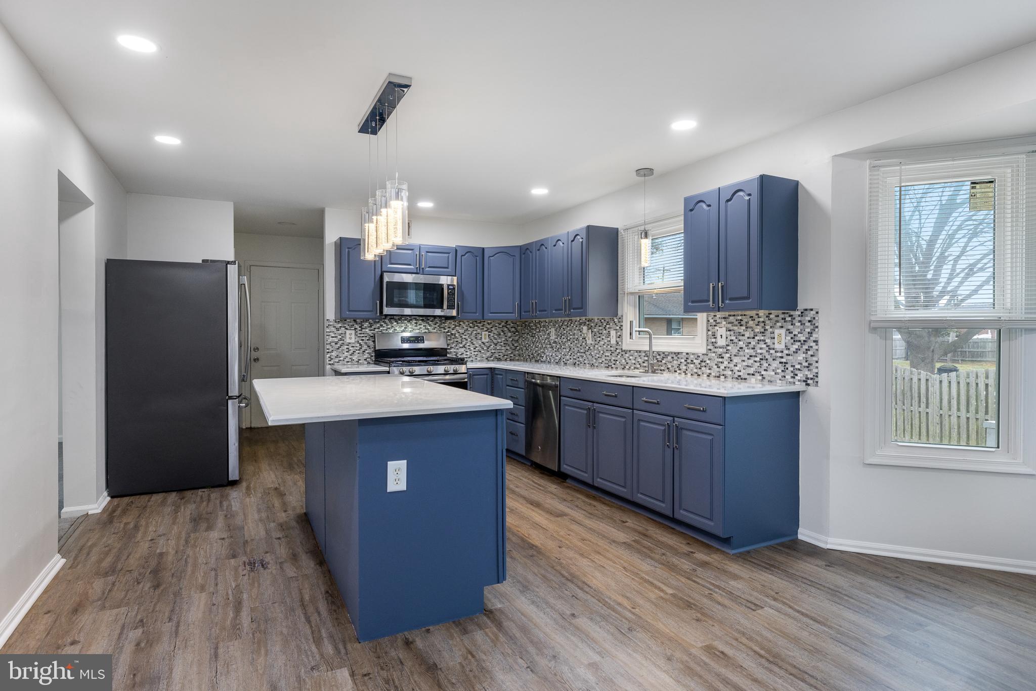 93 Nursery Drive Bear, DE 19701 - Photo 6 of 43 a kitchen with kitchen island granite countertop wooden floors stainless steel appliances a sink and a window