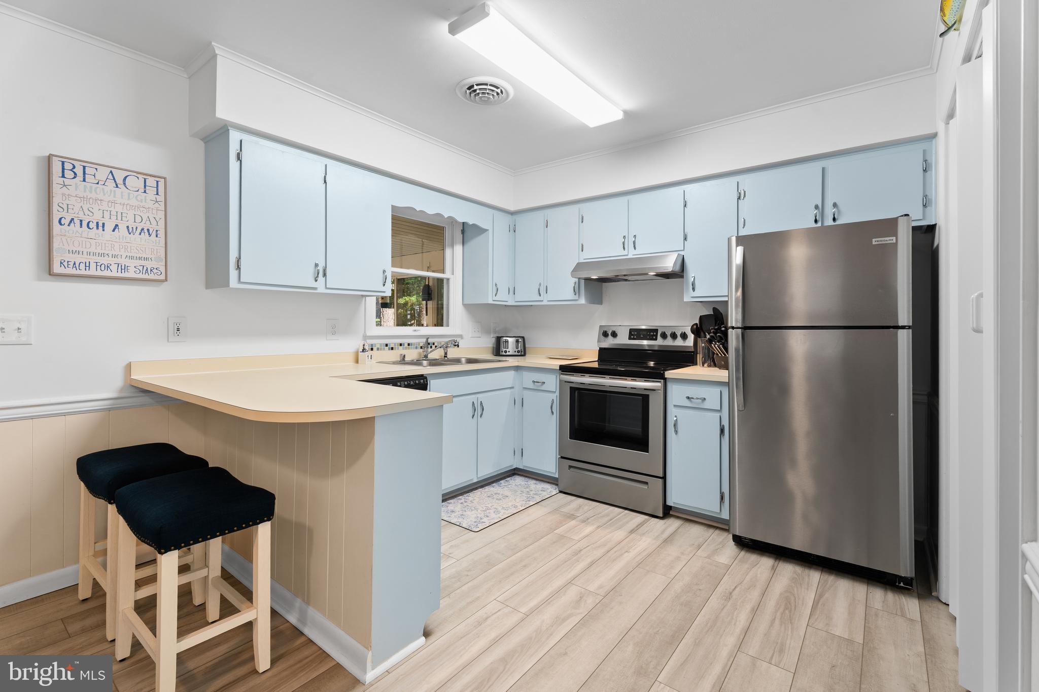 85 Ocean Parkway Ocean Pines, MD 21811 - Photo 17 of 78 a kitchen with a refrigerator a stove a sink dishwasher and white cabinets with wooden floor