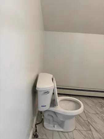 a white toilet sitting next to a white wall