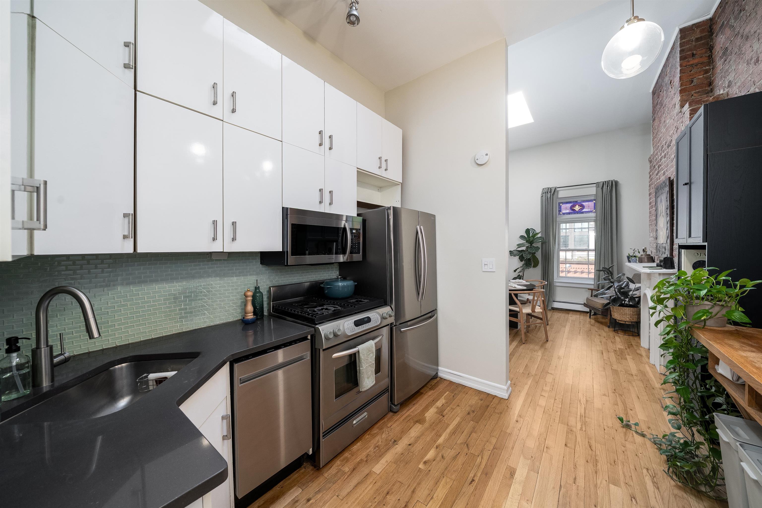 205 14th Street, Unit 4F Hoboken, NJ 07030 - Photo 9 of 22 a kitchen with stainless steel appliances a stove a sink cabinets and wooden floor