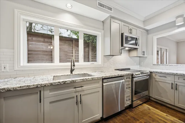 a kitchen with granite countertop stainless steel appliances sink stove and cabinets