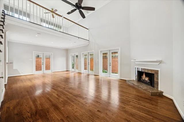 a view of an empty room with wooden floor fireplace and a window