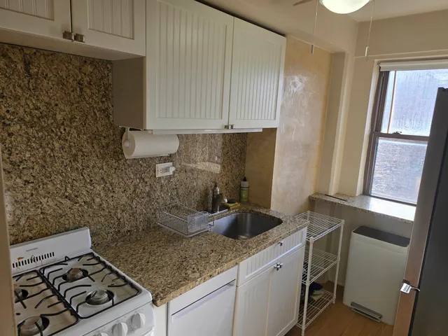 a kitchen with granite countertop a sink stove and cabinets