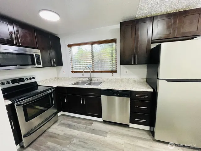 a kitchen with granite countertop a refrigerator stove and microwave