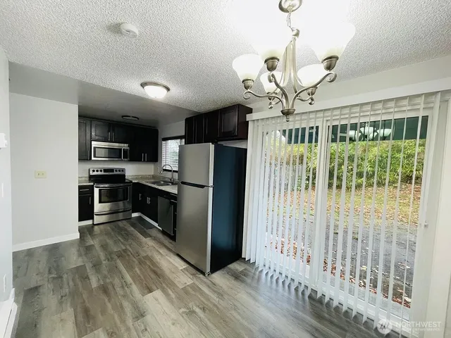 a kitchen with stainless steel appliances granite countertop a refrigerator a stove top oven a sink and dishwasher