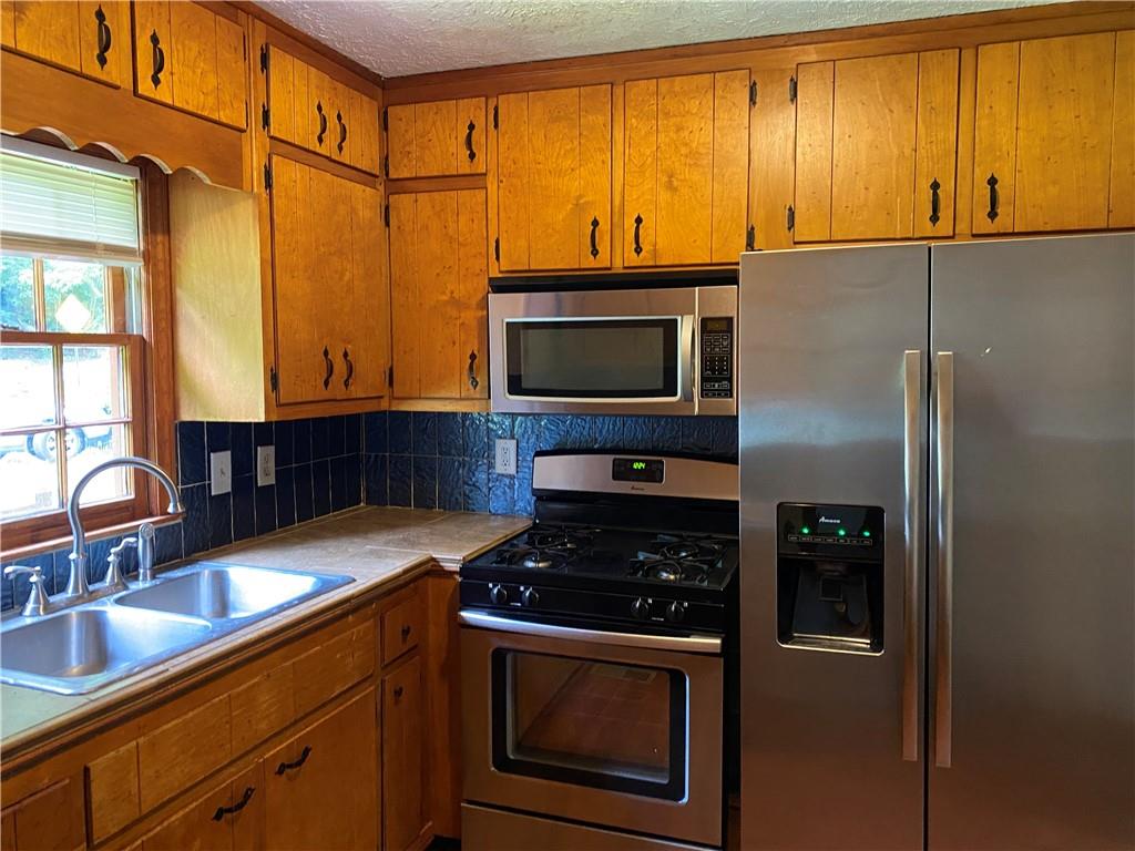 207 Hood Road Northwest Lilburn, GA 30047 - Photo 6 of 12 a kitchen with stainless steel appliances granite countertop a stove a refrigerator and a sink
