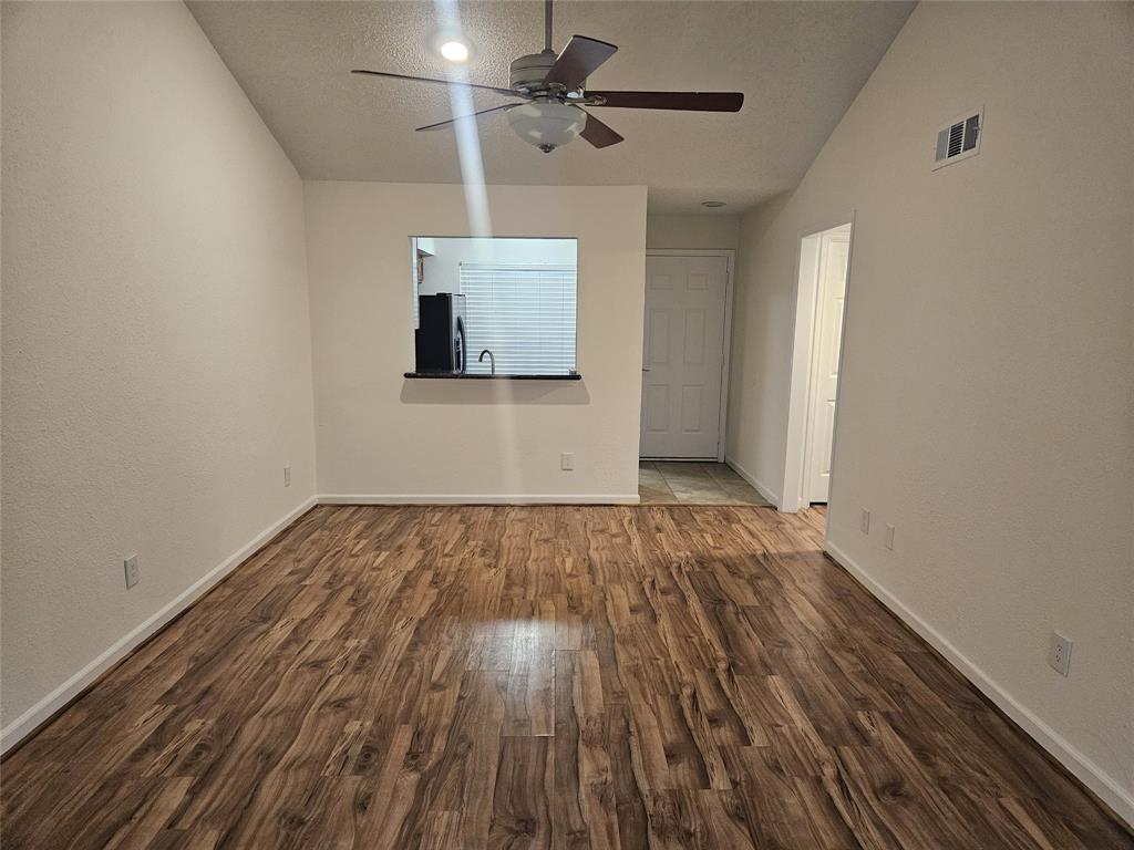 9601 Forest Lane, Unit 224 Dallas, TX 75243 - Photo 12 of 17 a view of an empty room with wooden floor and a ceiling fan