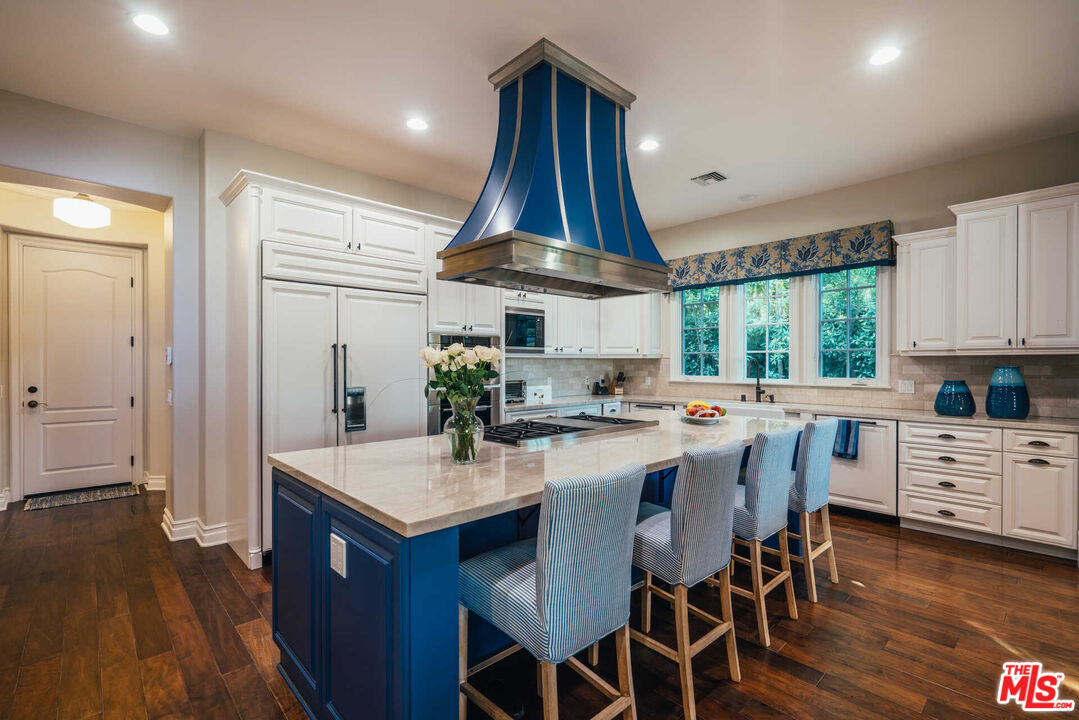 25311 Prado De Ambar Calabasas, CA 91302 - Photo 30 of 58 a kitchen with stainless steel appliances a dining table chairs stove and wooden floor