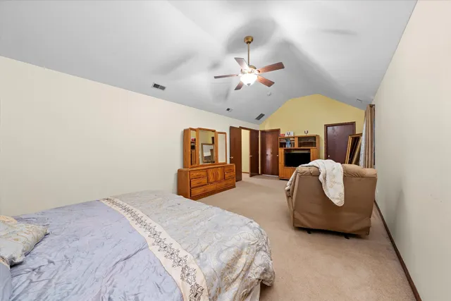 a spacious bedroom with a bed a chandelier and a couch