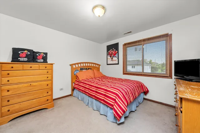 a bedroom with a bed and a flat tv screen on dresser