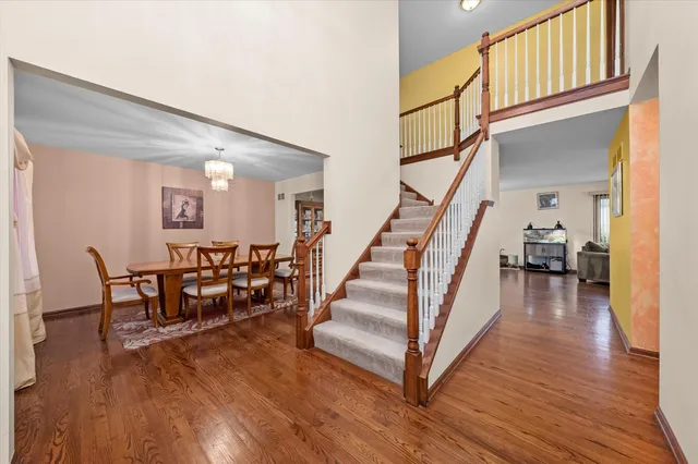 a dining room with wooden floor windows and a kitchen view