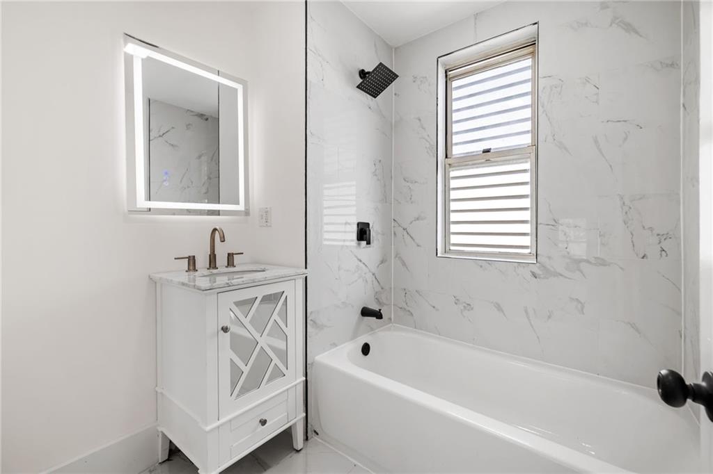 23 Craighead Street Pittsburgh, PA 15211 - Photo 27 of 35 a bathroom with a bathtub a mirror a sink and a window