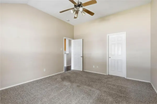an empty room with closet and a ceiling fan