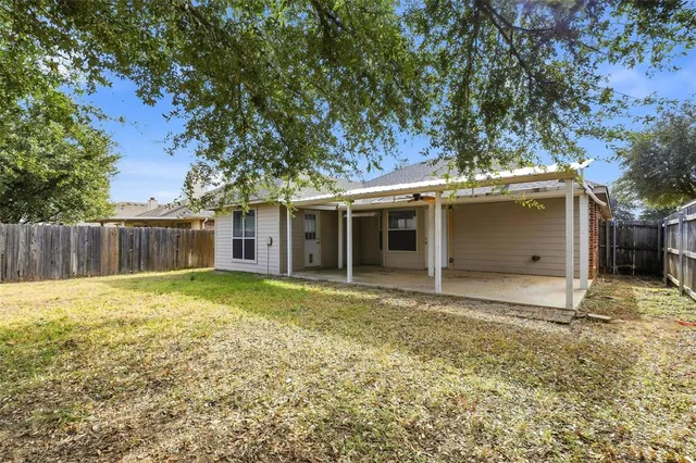 a view of a house with a yard and large tree