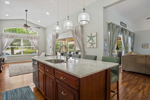 a kitchen with kitchen island granite countertop a sink a counter space appliances and cabinets