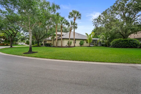 a view of a house with a big yard and large trees