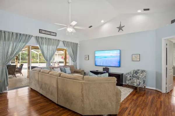 a living room with furniture a large window and wooden floor