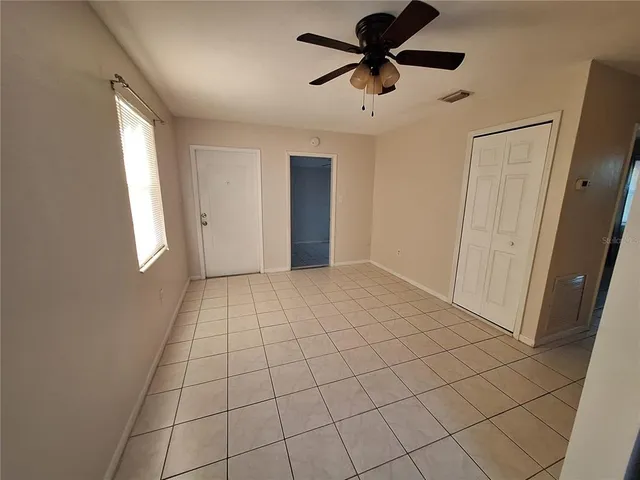 a view of an empty room and window with a chandelier fan