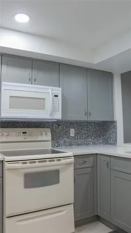 a kitchen with granite countertop white cabinets and white appliances