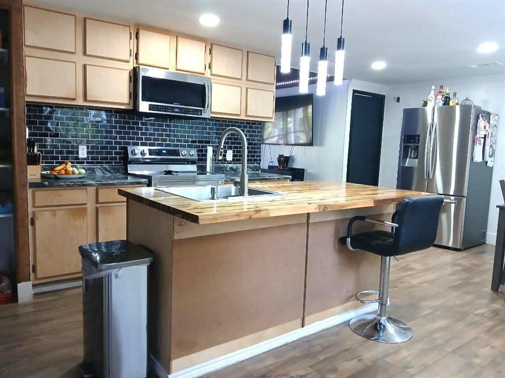 9153 Bouncer Road Quinlan, TX 75474 - Photo 7 of 27 a kitchen with stainless steel appliances granite countertop a sink a stove a refrigerator cabinets a dining table and chairs