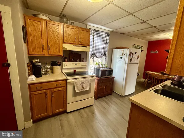 a kitchen with a refrigerator a stove a sink dishwasher and wooden cabinets with wooden floor