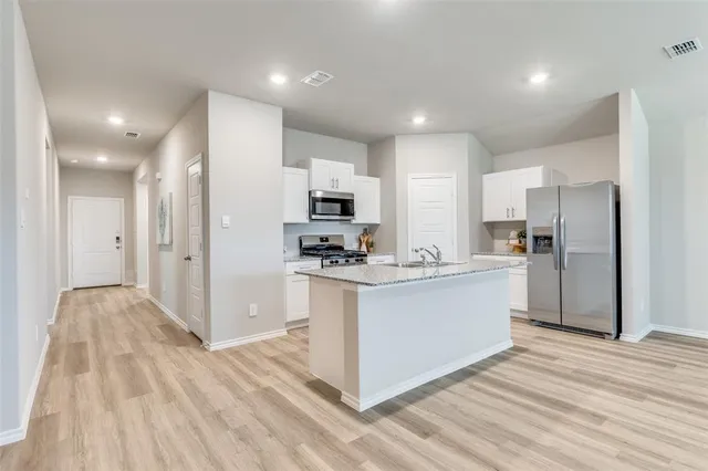 a kitchen with stainless steel appliances kitchen island granite countertop a refrigerator and a sink