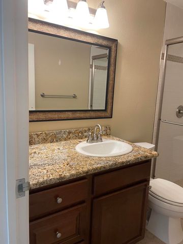 a bathroom with a granite countertop bathtub shower sink vanity and toilet