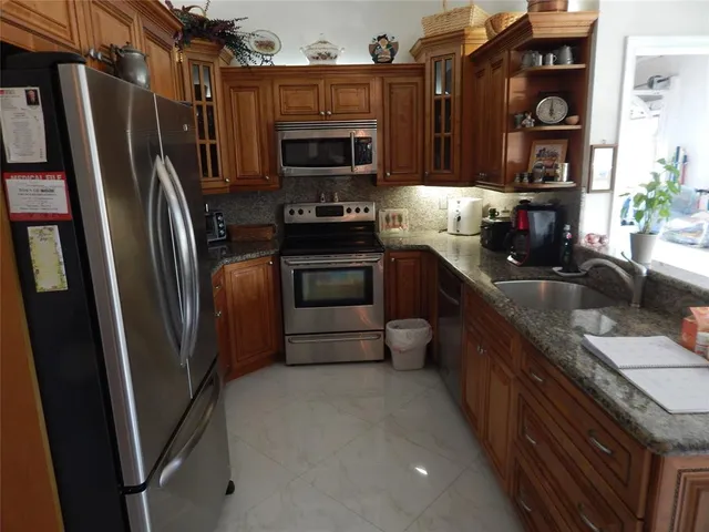 a kitchen with granite countertop a refrigerator and a sink
