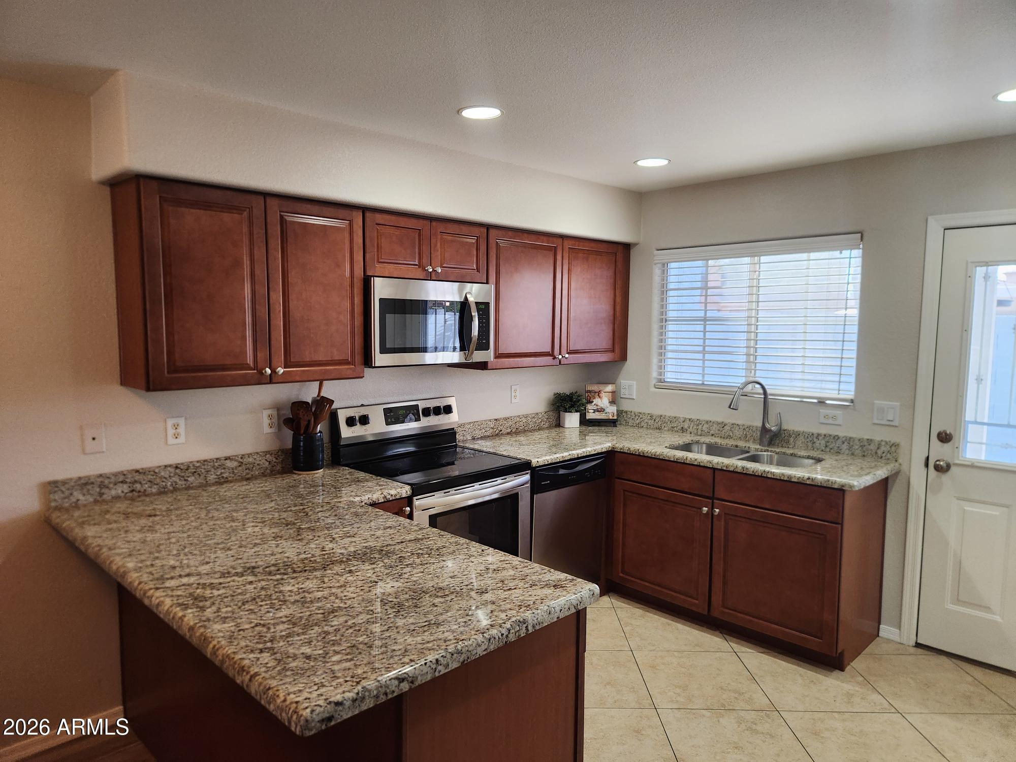 860 North McQueen Road, Unit 1145 Chandler, AZ 85225 - Photo 10 of 63 a kitchen with granite countertop wooden cabinets a sink dishwasher stove and microwave